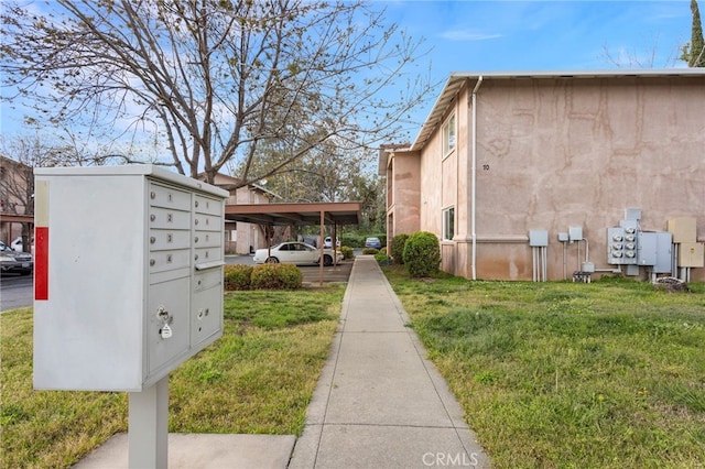 view of home's exterior featuring a yard, stucco siding, and mail area