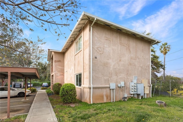 view of side of home with a yard, stucco siding, and fence