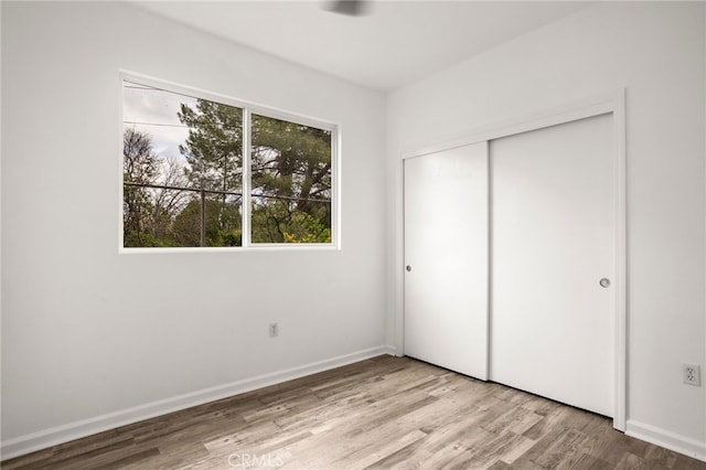 unfurnished bedroom with a closet, baseboards, and wood finished floors