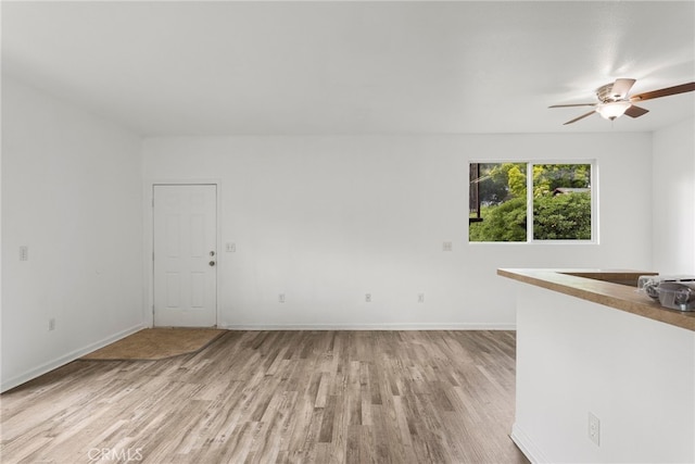 empty room with light wood-type flooring, baseboards, and a ceiling fan