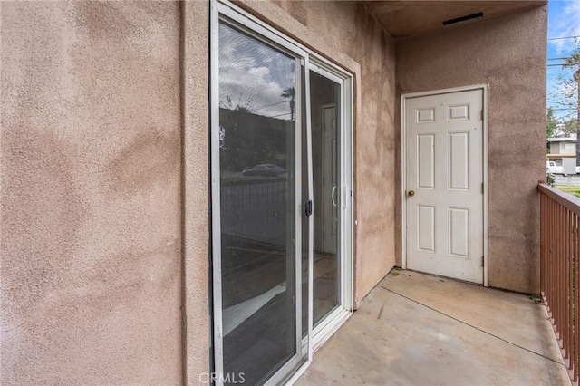 entrance to property featuring a balcony and stucco siding