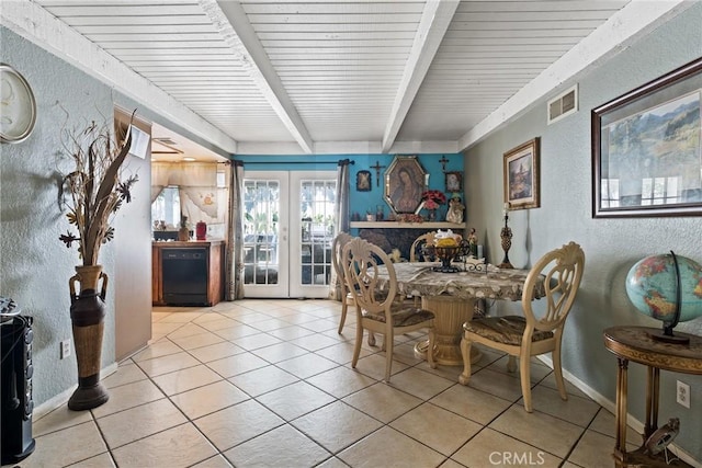 dining room with a textured wall, beam ceiling, light tile patterned floors, french doors, and baseboards