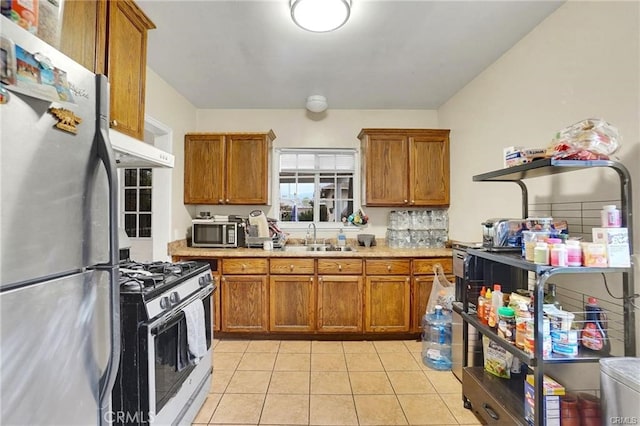 13031305 E Kingsley Ave, Pomona, CA 91767 - kitchen with brown cabinetry, light tile patterned floors, a sink, and stainless steel appliances