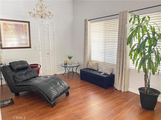 living area featuring an inviting chandelier, wood finished floors, and baseboards