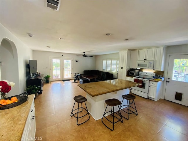 kitchen featuring visible vents, white appliances, and a healthy amount of sunlight
