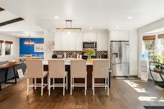 kitchen with white cabinets, dark wood finished floors, decorative backsplash, and appliances with stainless steel finishes