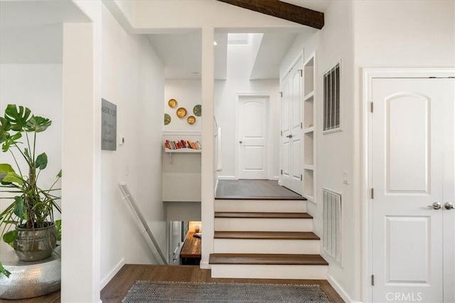 stairway featuring visible vents, wood finished floors, and beamed ceiling