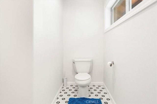 bathroom featuring tile patterned flooring, baseboards, and toilet