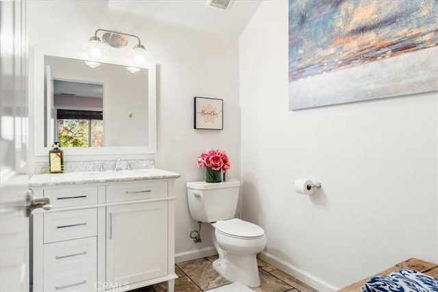 bathroom featuring toilet, vanity, and baseboards