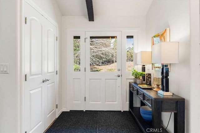 entryway with beamed ceiling and dark colored carpet