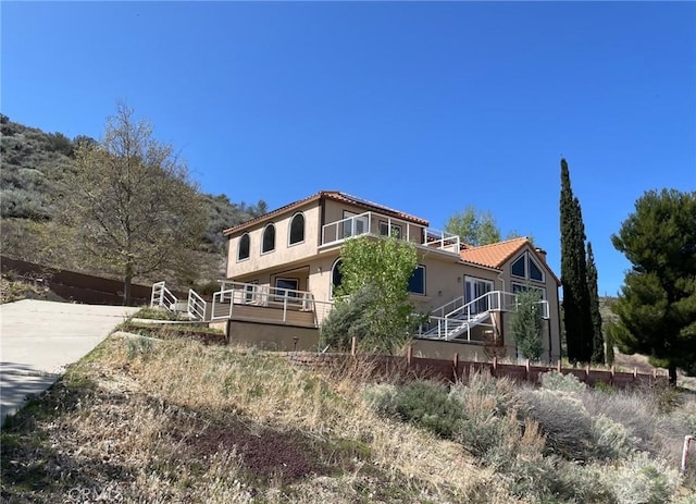 back of house featuring stucco siding and a tile roof