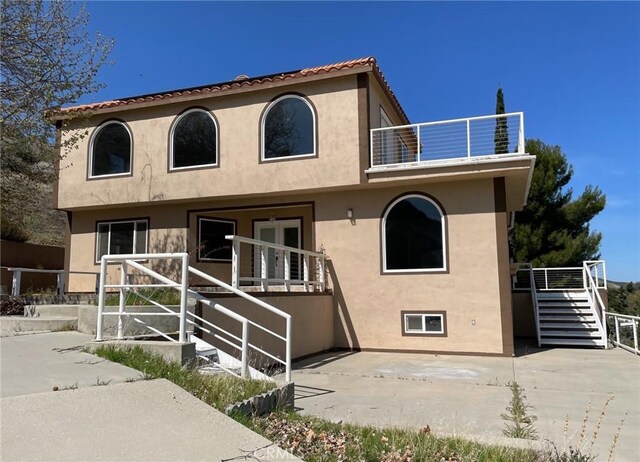 exterior space with a patio, stairway, stucco siding, and a balcony