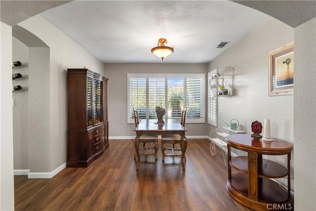 dining room featuring arched walkways, dark wood-style flooring, baseboards, and visible vents