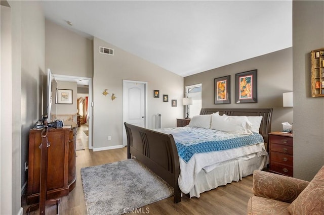 bedroom with visible vents, baseboards, high vaulted ceiling, and wood finished floors