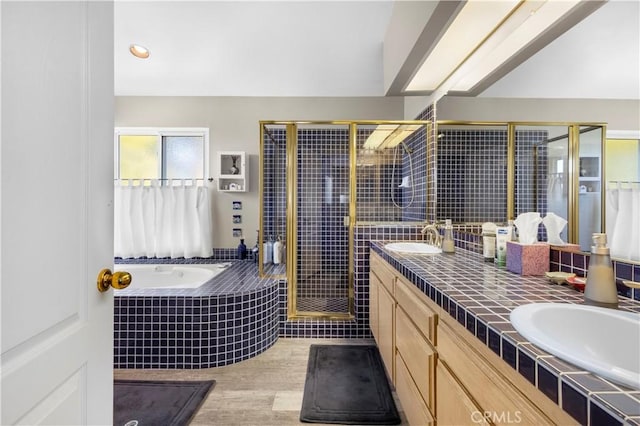 full bathroom with a sink, a shower stall, double vanity, wood finished floors, and a garden tub