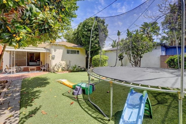 view of yard with a trampoline and a patio