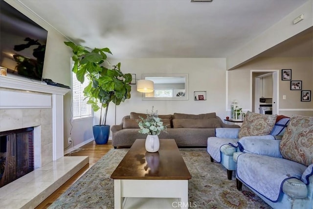 living area with wood finished floors, a high end fireplace, and baseboards