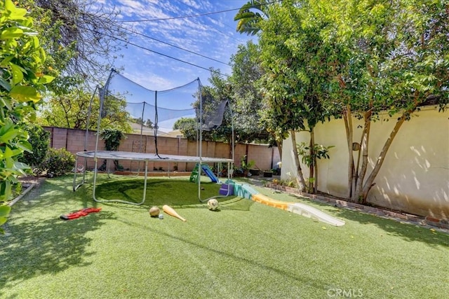 view of yard with a trampoline and a fenced backyard