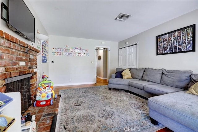 living area featuring visible vents, baseboards, wood finished floors, and a fireplace