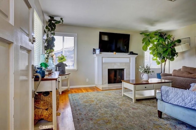 living area featuring a tile fireplace, wood finished floors, and baseboards