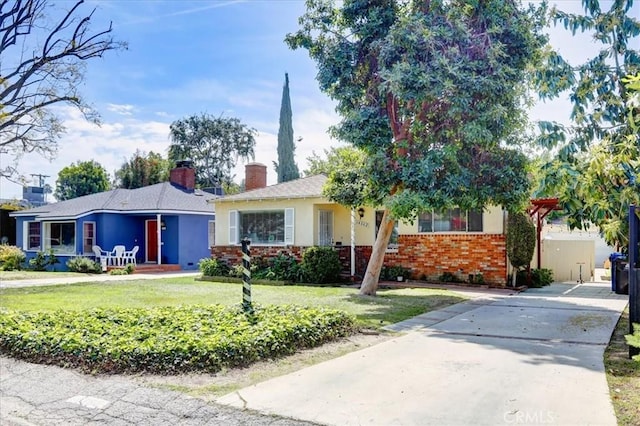 single story home featuring stucco siding, a chimney, driveway, a front lawn, and brick siding