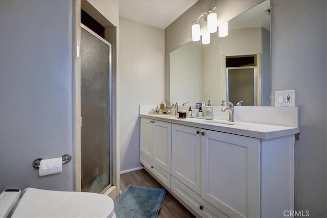 bathroom featuring a sink, a shower stall, and wood finished floors