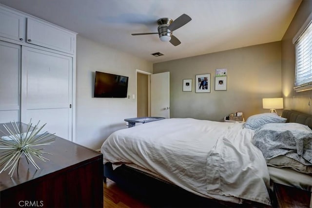 bedroom with dark wood-style floors, a closet, a ceiling fan, and visible vents