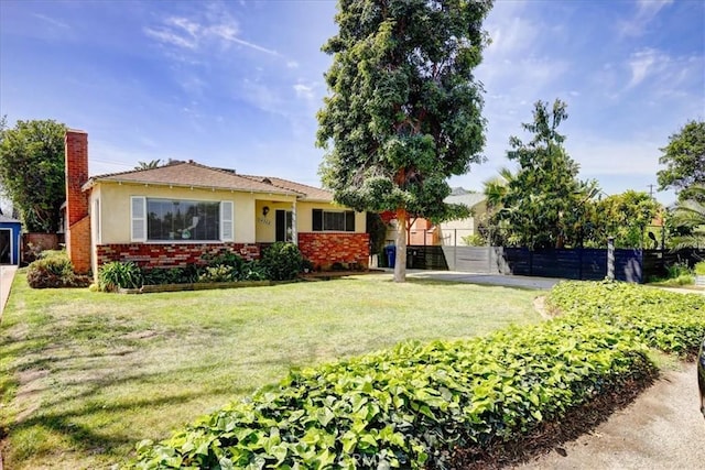 view of front of home featuring stucco siding, fence, a front lawn, brick siding, and a chimney