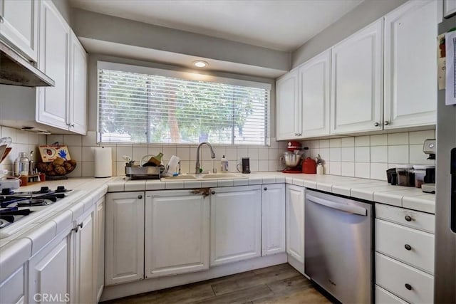 kitchen with stainless steel dishwasher, a sink, white cabinets, and plenty of natural light