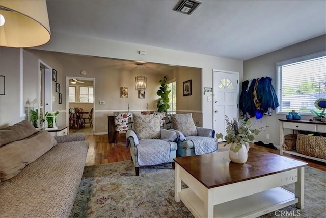 living room with wood finished floors, a notable chandelier, visible vents, and a wealth of natural light