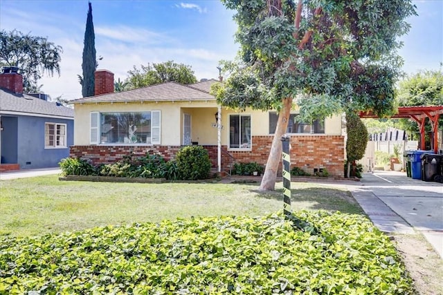 view of front of home with a chimney, a front yard, stucco siding, and brick siding