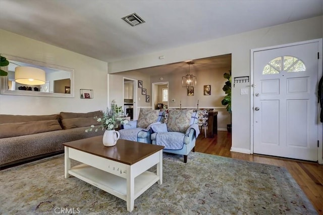 living area featuring a healthy amount of sunlight, visible vents, a chandelier, and wood finished floors