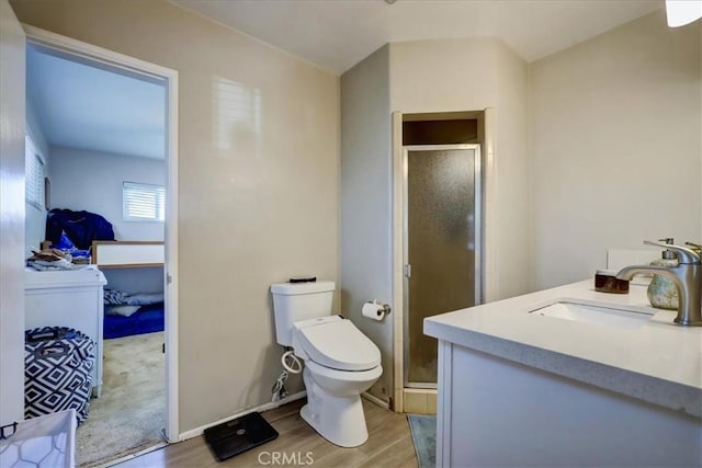 bathroom with baseboards, toilet, a shower stall, vanity, and wood finished floors