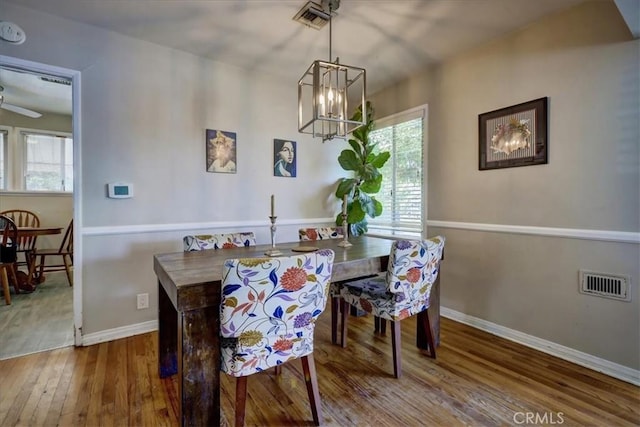 dining area with visible vents, baseboards, wood-type flooring, and a notable chandelier