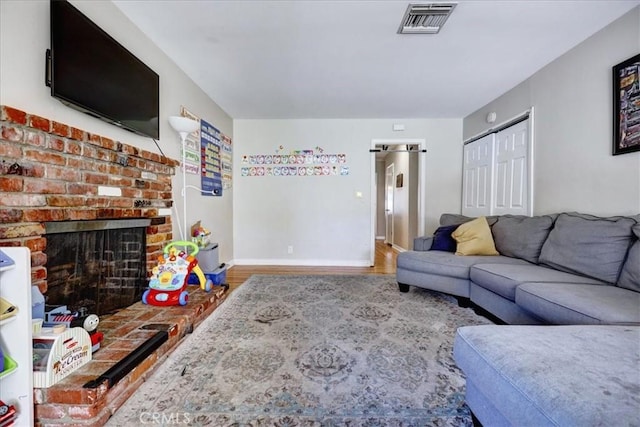 living area with visible vents, baseboards, wood finished floors, and a fireplace