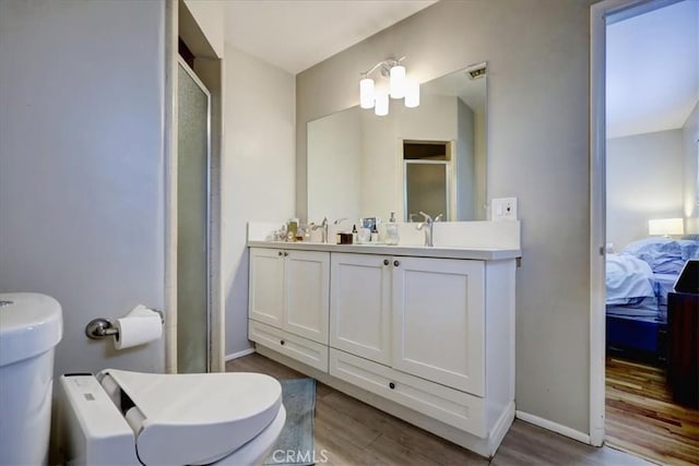 ensuite bathroom with a shower stall, ensuite bathroom, double vanity, and wood finished floors
