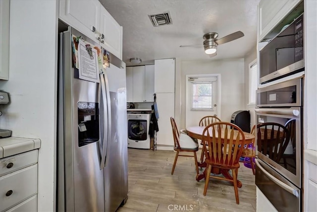kitchen with washer / clothes dryer, visible vents, tile counters, a warming drawer, and stainless steel appliances