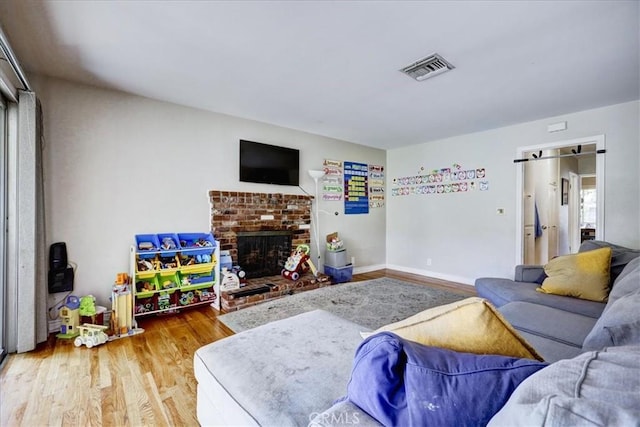 living area with a fireplace, visible vents, baseboards, and wood finished floors