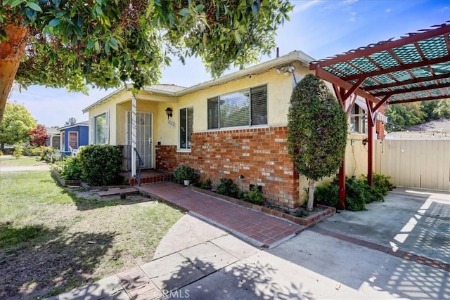 view of front facade with stucco siding, fence, a front lawn, and brick siding