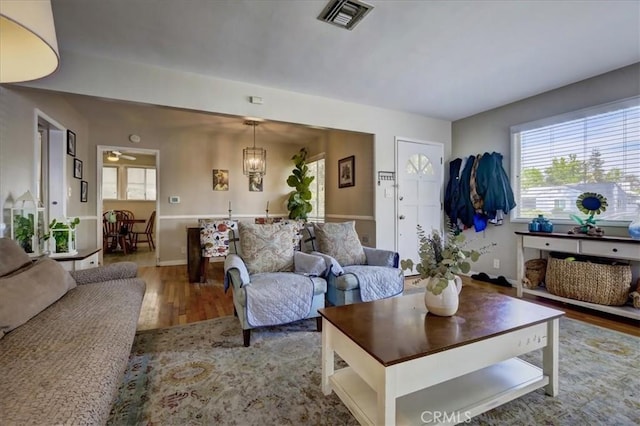 living area featuring visible vents, baseboards, a notable chandelier, and wood finished floors