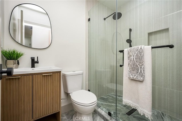 full bath with vanity, marble finish floor, a tile shower, and toilet