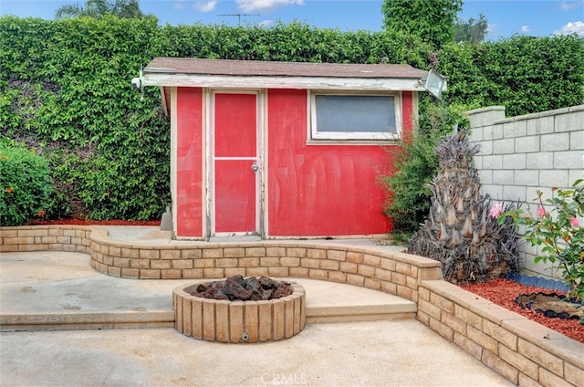 view of shed with fence and a fire pit
