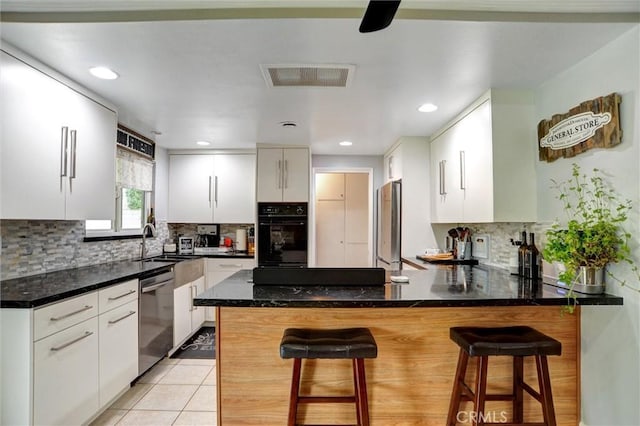 kitchen with white cabinets, stainless steel appliances, visible vents, decorative backsplash, and a peninsula