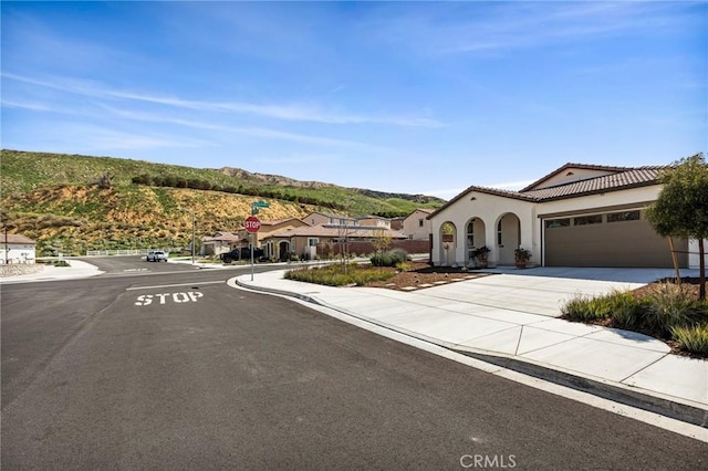 mediterranean / spanish house with stucco siding, driveway, a garage, and a tile roof