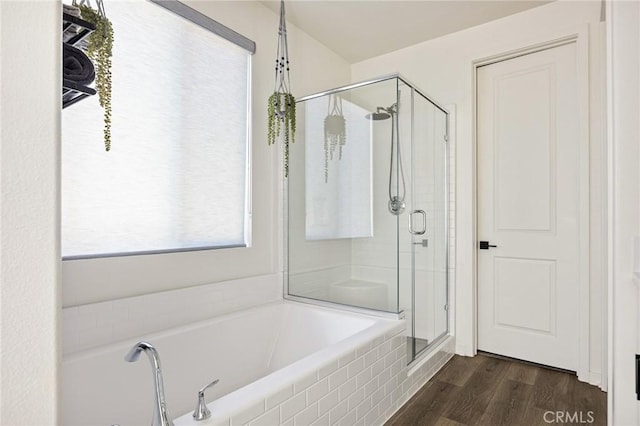 bathroom featuring a stall shower, wood finished floors, and a garden tub