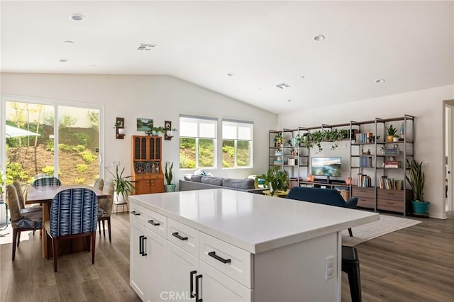 kitchen featuring white cabinetry, wood finished floors, light countertops, lofted ceiling, and open floor plan