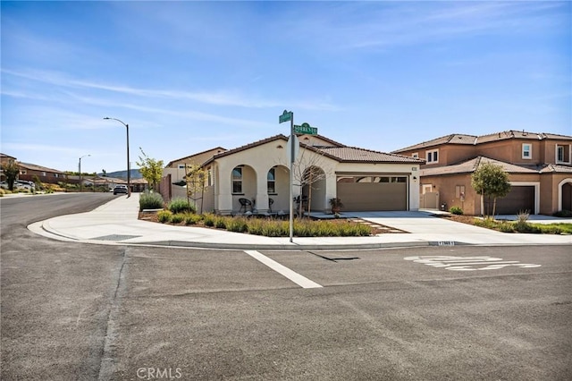 view of front of house featuring a tile roof, stucco siding, a garage, and concrete driveway
