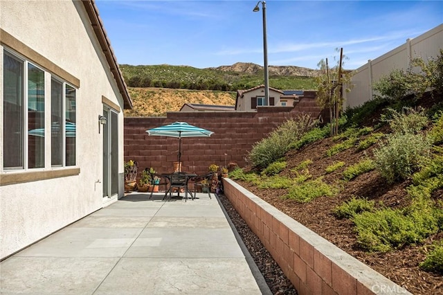 view of patio / terrace with outdoor dining space, a mountain view, and fence