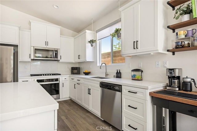 kitchen featuring white cabinets, a sink, light countertops, appliances with stainless steel finishes, and lofted ceiling