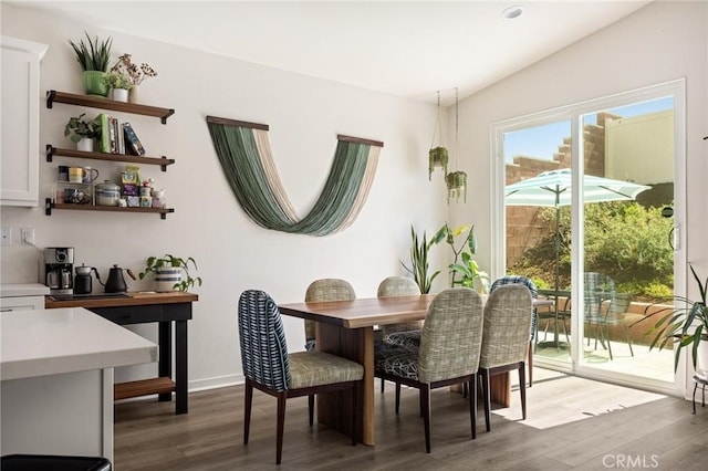 dining room featuring wood finished floors, baseboards, and vaulted ceiling